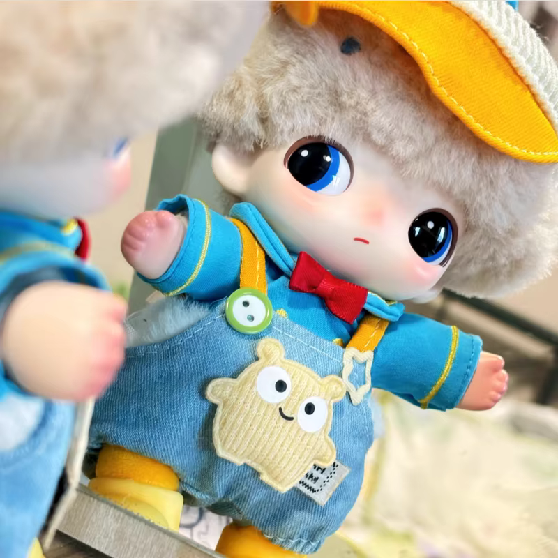 The Dimoo plastic doll set of hat, clothes, and shoes also has a matching pair of overalls and is 17cm in length.